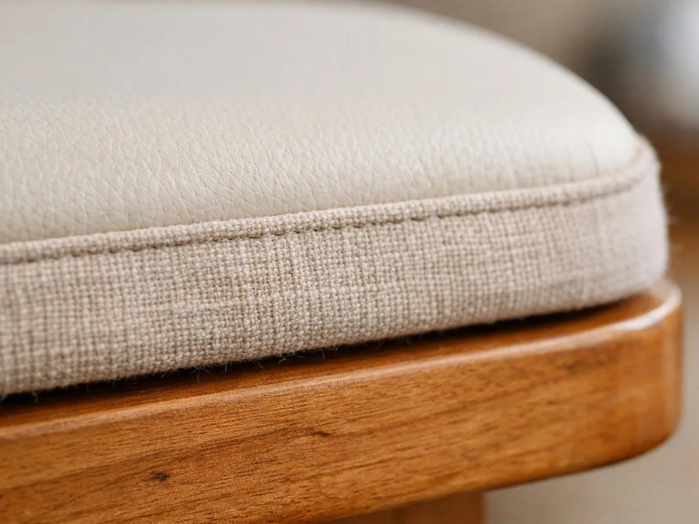Close-up of a beige cushioned seat with textured fabric resting on a wooden frame